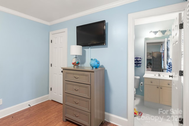 bedroom featuring ornamental molding, sink, ensuite bathroom, and light wood-type flooring