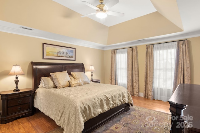 bedroom featuring hardwood / wood-style floors, crown molding, a raised ceiling, and ceiling fan