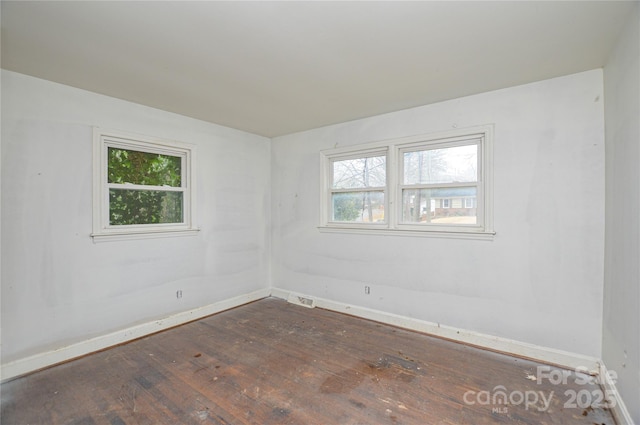 empty room featuring dark wood-type flooring and a wealth of natural light