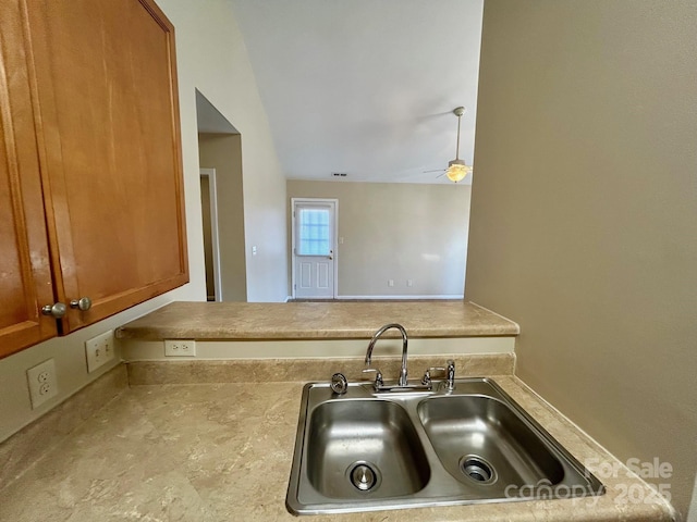 kitchen with a ceiling fan, brown cabinetry, and a sink