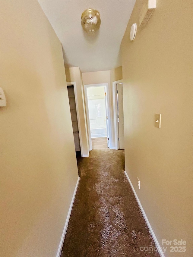 hallway featuring concrete floors and baseboards