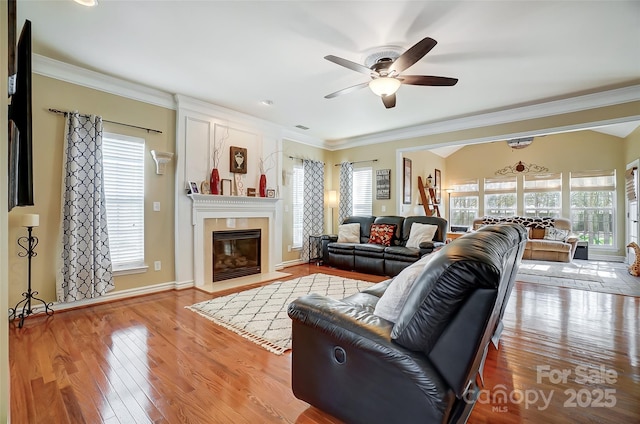 living area with light wood-style floors, a healthy amount of sunlight, and ornamental molding