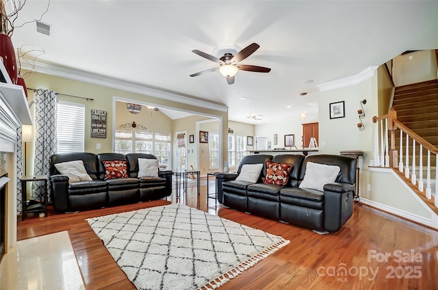 living room with ceiling fan, light wood-style flooring, baseboards, ornamental molding, and stairway