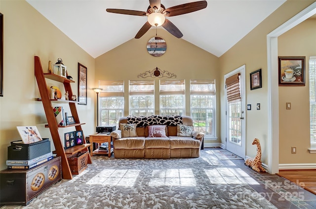 living room featuring vaulted ceiling, plenty of natural light, a ceiling fan, and baseboards