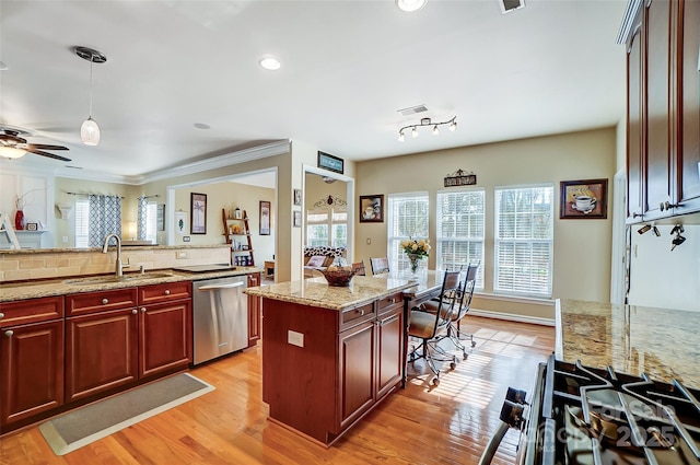 kitchen with dishwasher, a kitchen island, hanging light fixtures, light stone countertops, and a sink