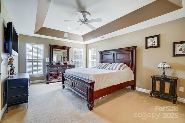 bedroom featuring baseboards, ceiling fan, a raised ceiling, and light colored carpet