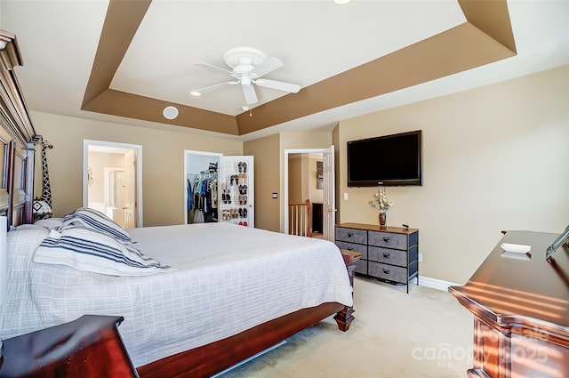 bedroom featuring a tray ceiling, a closet, light colored carpet, a spacious closet, and connected bathroom