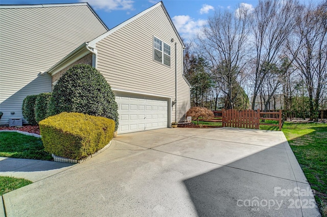 view of side of home featuring a garage, driveway, and fence