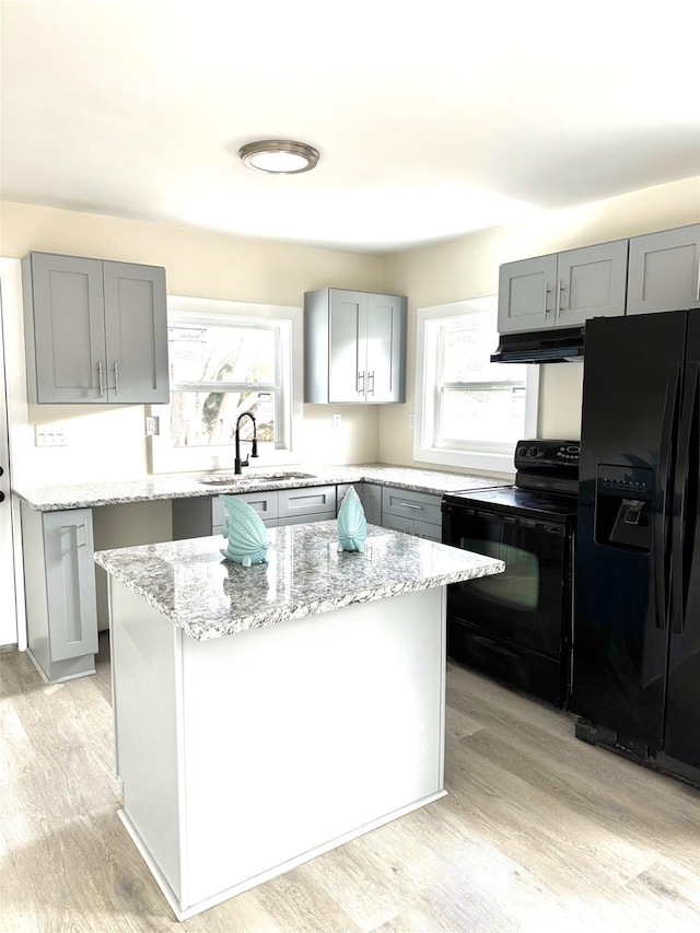 kitchen with light stone countertops, plenty of natural light, black appliances, and a center island