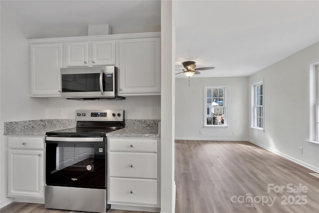 kitchen featuring white cabinetry, light stone counters, light wood-type flooring, and appliances with stainless steel finishes