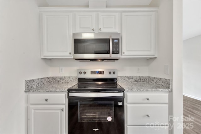 kitchen with electric stove, light stone countertops, and white cabinets