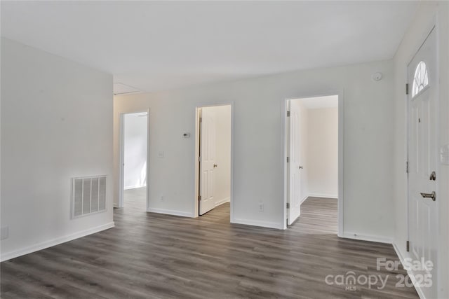 unfurnished bedroom with dark wood-type flooring, a walk in closet, and a closet