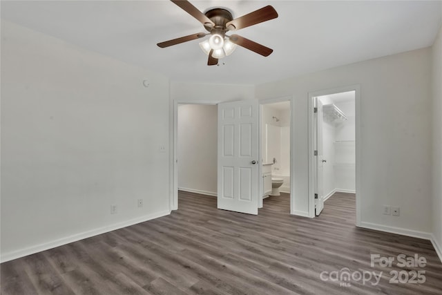 unfurnished bedroom with a walk in closet, dark wood-type flooring, ceiling fan, and a closet