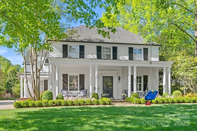 view of front facade with driveway, covered porch, and a front yard