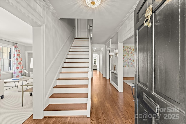 stairway featuring ornamental molding, wood finished floors, and a decorative wall