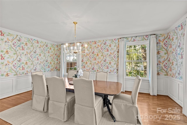 dining space featuring wallpapered walls, light wood-style floors, an inviting chandelier, and wainscoting