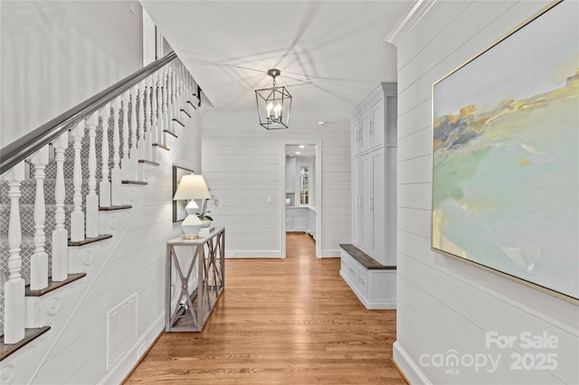 hallway featuring baseboards, visible vents, an inviting chandelier, stairs, and light wood-style floors