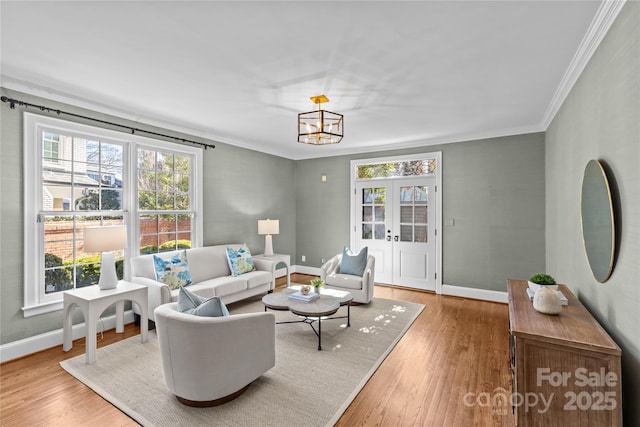 living area featuring ornamental molding, baseboards, and wood finished floors