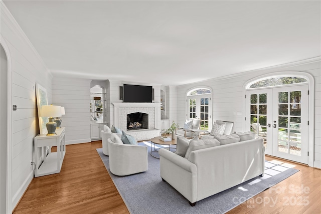 living area with french doors, a fireplace, wood finished floors, and a wealth of natural light