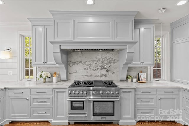 kitchen featuring range with two ovens, white cabinetry, and light stone counters