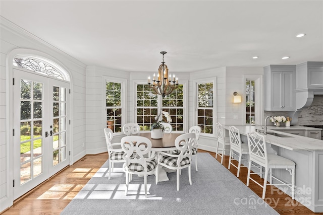 dining room featuring french doors, light wood-type flooring, recessed lighting, and an inviting chandelier