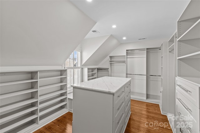 spacious closet with dark wood-style floors, visible vents, and vaulted ceiling