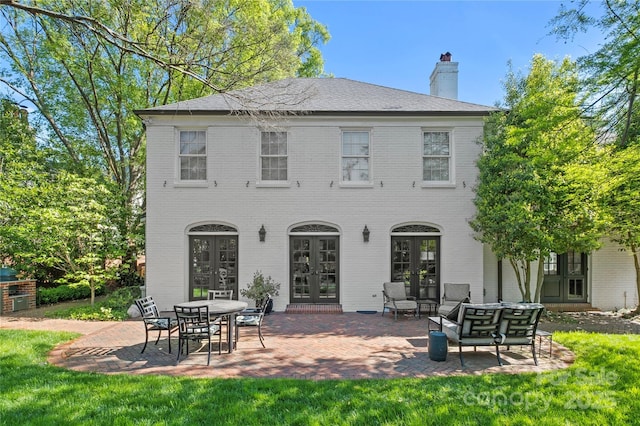 back of house with brick siding, a chimney, and french doors