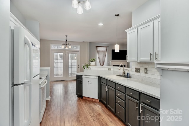 kitchen featuring pendant lighting, sink, white appliances, white cabinetry, and light wood-type flooring