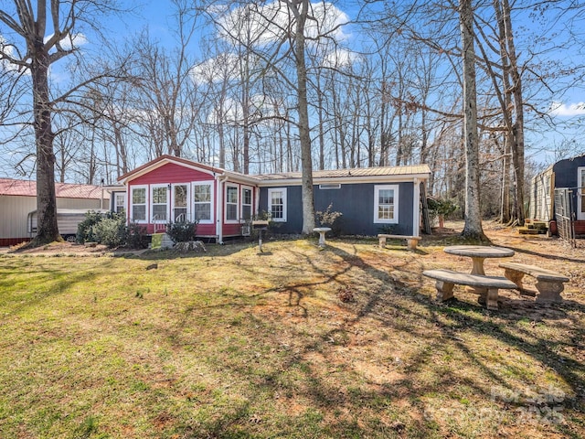 view of front of house with metal roof, a front lawn, and a sunroom