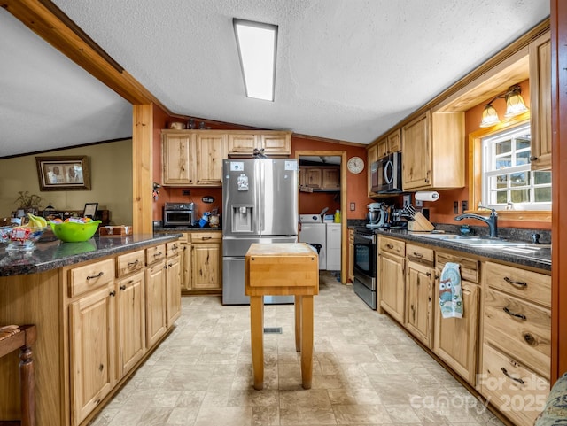 kitchen featuring stainless steel appliances, washing machine and dryer, lofted ceiling, and dark countertops