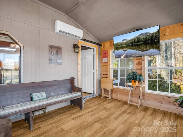 interior space featuring lofted ceiling, light wood-type flooring, wood walls, and a wall mounted air conditioner