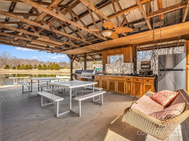 wooden deck featuring exterior kitchen, outdoor dining space, a sink, and grilling area