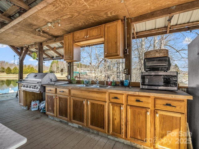 kitchen with stainless steel microwave, a sink, hardwood / wood-style flooring, and brown cabinets