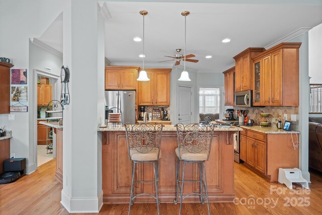 kitchen with ceiling fan, light stone countertops, stainless steel appliances, decorative backsplash, and ornamental molding
