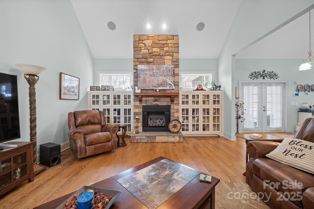 living area featuring wood finished floors, high vaulted ceiling, a wealth of natural light, and a fireplace