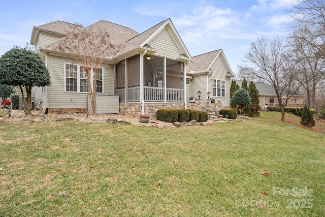 back of property featuring a sunroom, a shingled roof, and a lawn