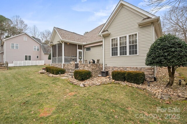 rear view of house with roof with shingles, a lawn, a sunroom, fence, and cooling unit