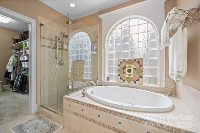 full bathroom featuring crown molding, a walk in closet, tile patterned flooring, a bath, and a stall shower