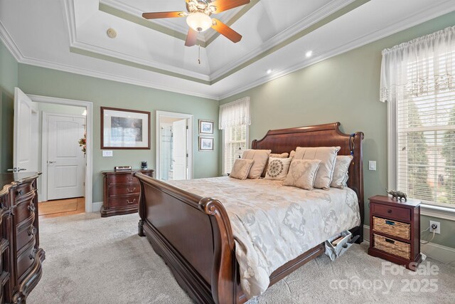bedroom with crown molding, light colored carpet, multiple windows, and a raised ceiling