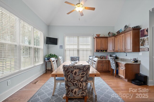 dining room with ceiling fan, baseboards, lofted ceiling, and light wood-type flooring