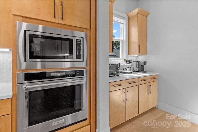 kitchen with light brown cabinets, appliances with stainless steel finishes, light countertops, and a sink