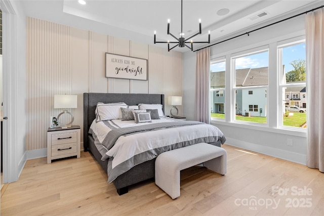 bedroom with a chandelier, light wood finished floors, visible vents, and baseboards