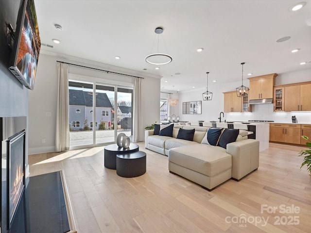 living area featuring light wood-style floors, a warm lit fireplace, baseboards, and recessed lighting