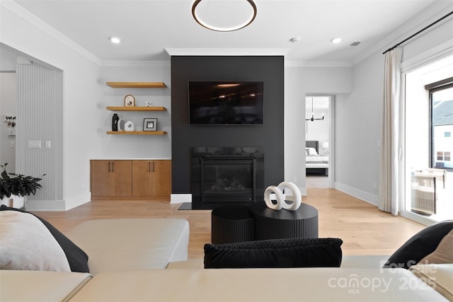 living room featuring light wood finished floors, a fireplace with flush hearth, ornamental molding, and baseboards