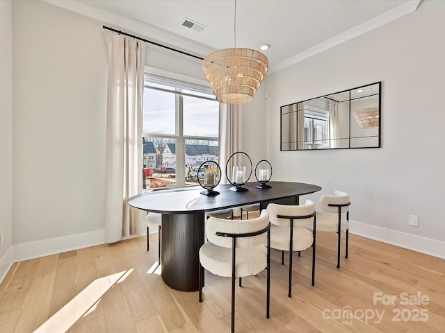 dining room featuring baseboards, light wood finished floors, visible vents, and crown molding