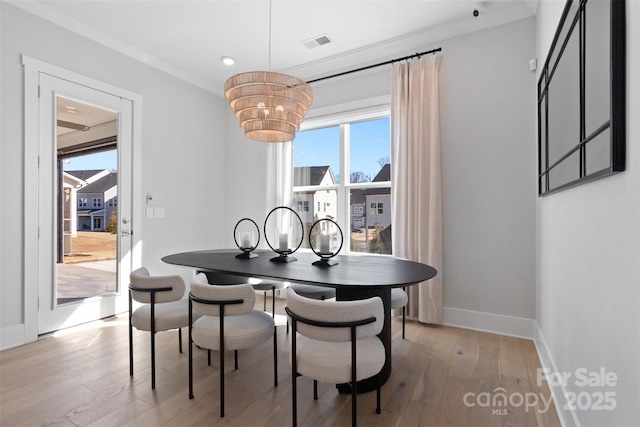 dining space featuring light wood-type flooring, baseboards, visible vents, and crown molding