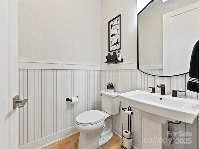 bathroom with wainscoting, wood finished floors, and toilet