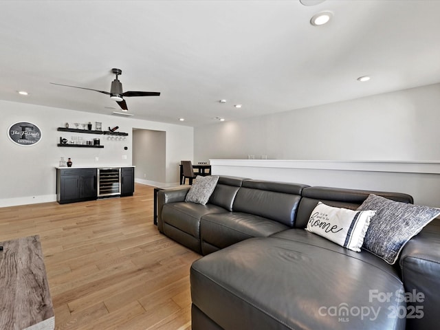 living area with beverage cooler, baseboards, light wood-style flooring, a bar, and recessed lighting