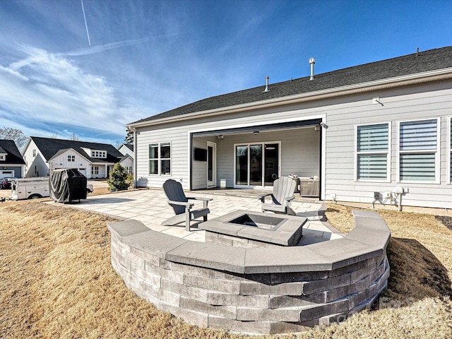 rear view of house with a fire pit and a patio