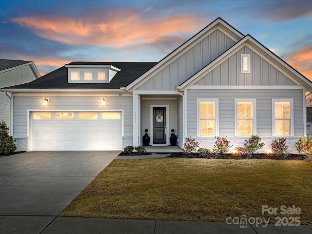 view of front of property featuring a shingled roof, a lawn, an attached garage, board and batten siding, and driveway